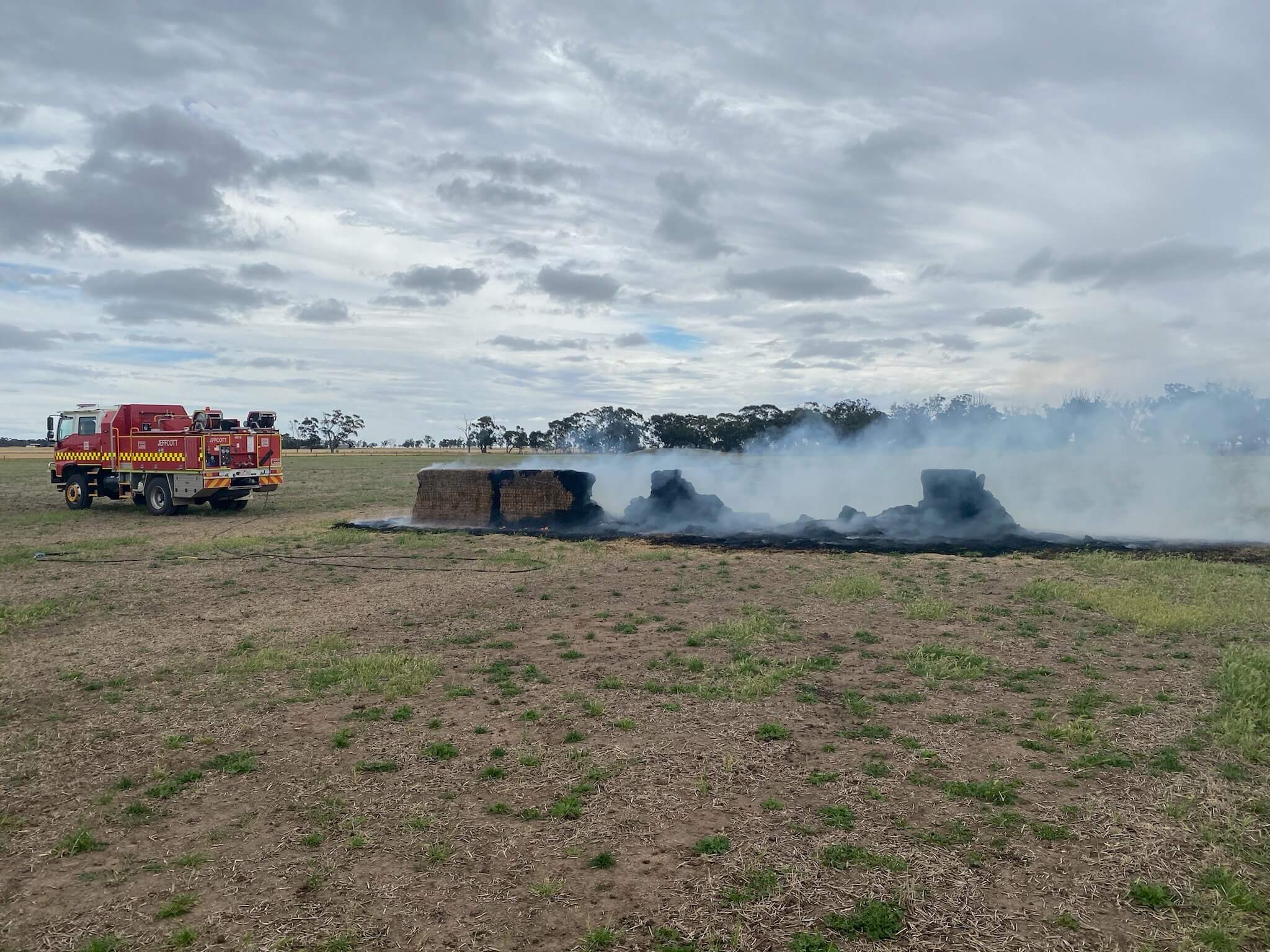 Hay bales on fire with fire truck in background